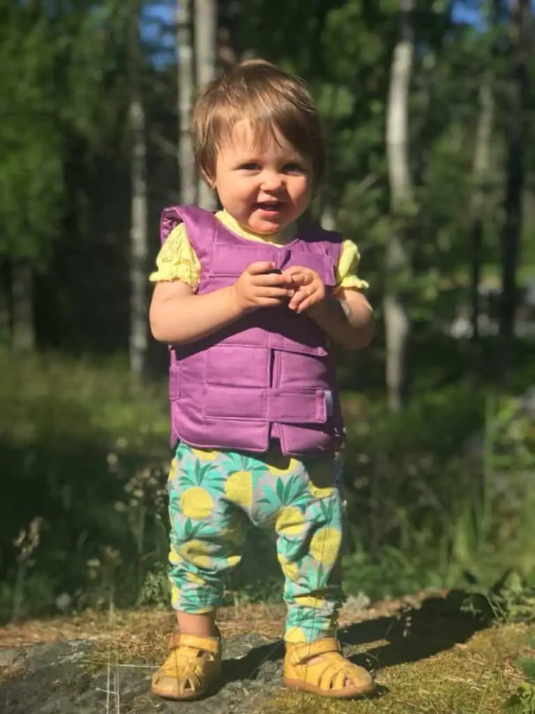 Ett litet barn använder en lila kylväst utomhus